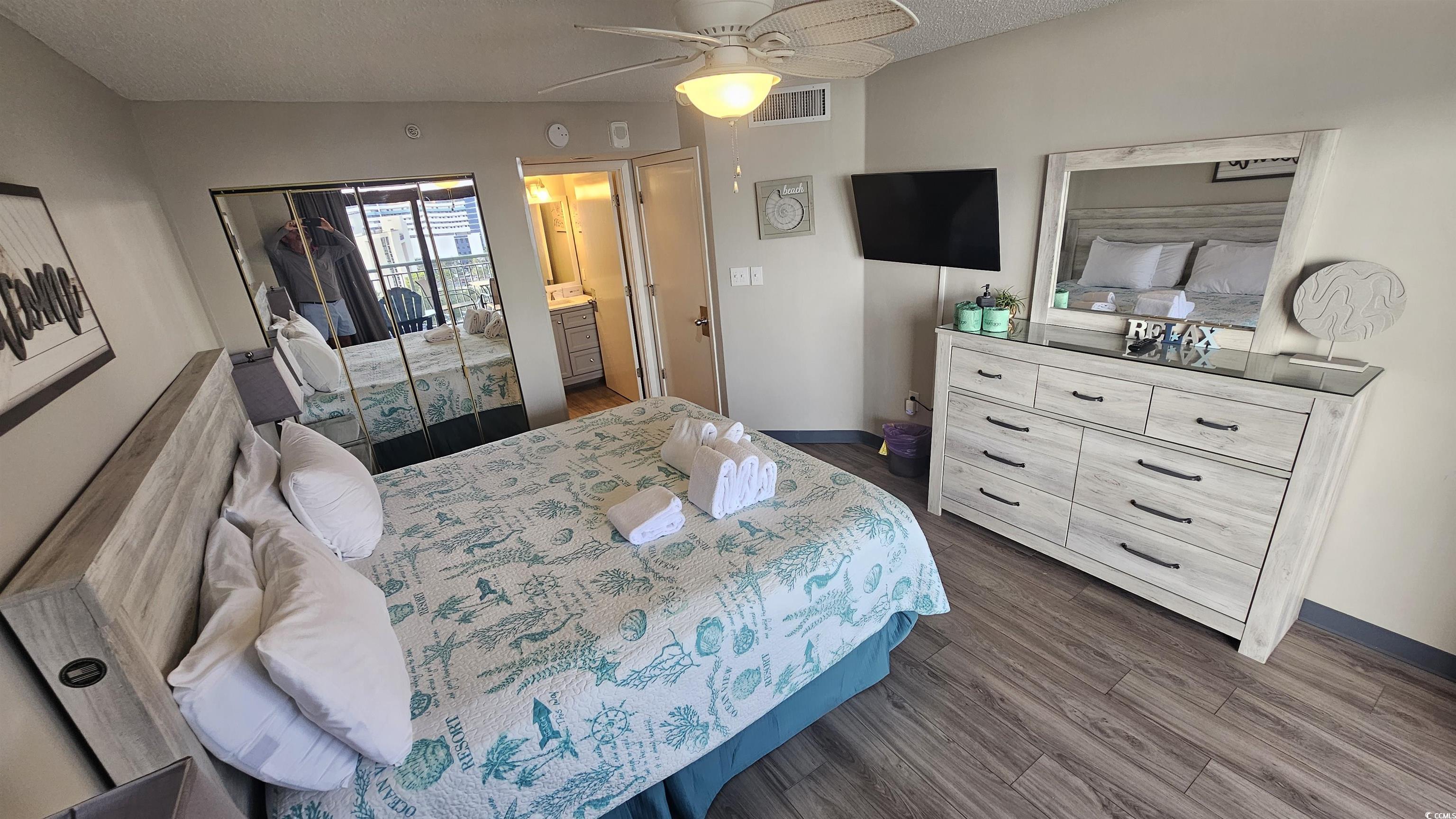 201 74th Avenue North, Unit 1201 Myrtle Beach, SC 29572 - Photo 2 of 40 Bedroom with dark wood-style flooring, a closet, a textured ceiling, ceiling fan, and ensuite bath