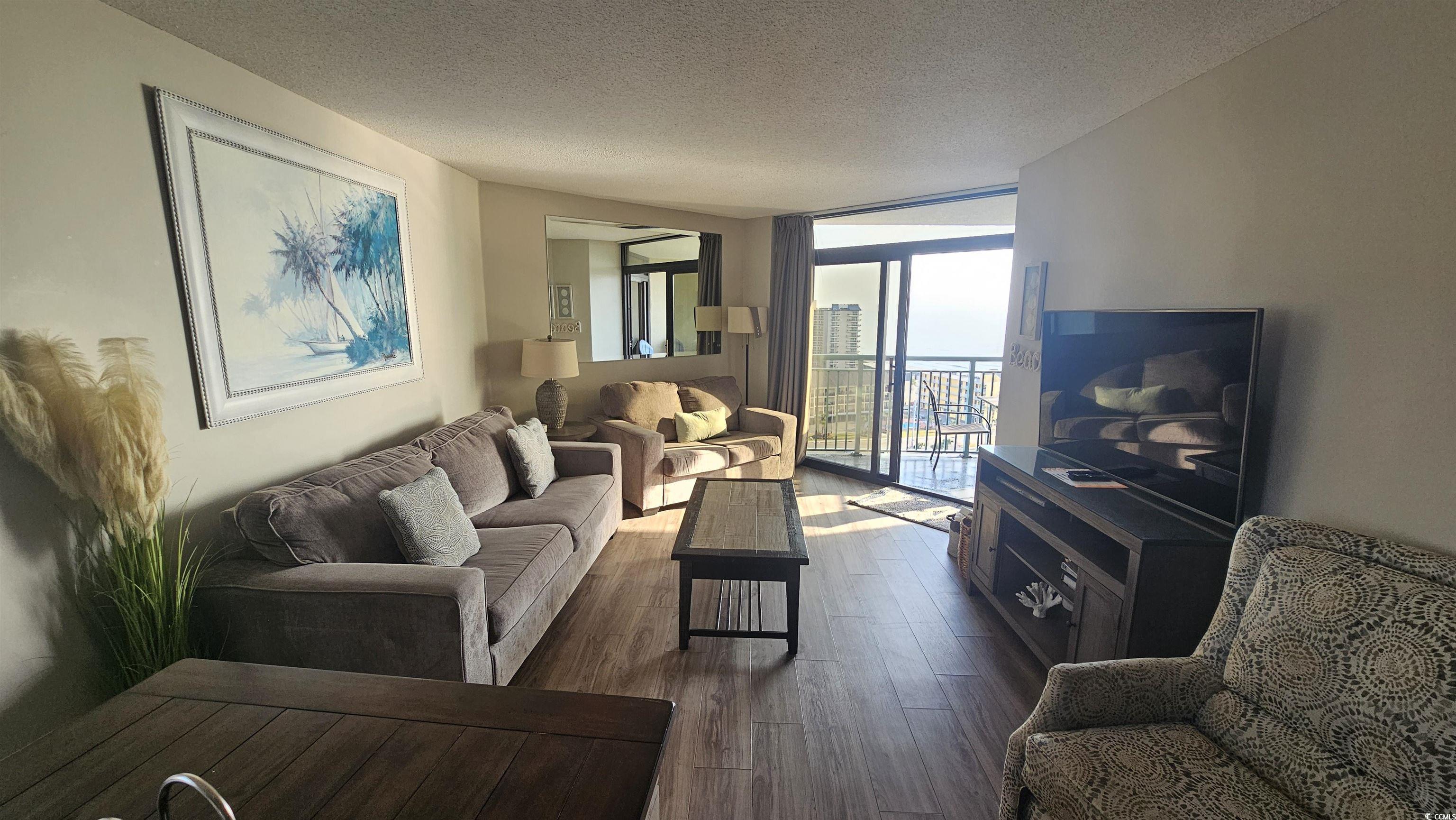 201 74th Avenue North, Unit 1201 Myrtle Beach, SC 29572 - Photo 5 of 40 Living area featuring a wall of windows, dark wood-style flooring, and a textured ceiling