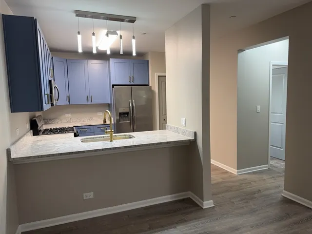 a kitchen with kitchen island stainless steel appliances a sink and a refrigerator