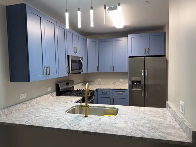 a kitchen with kitchen island granite countertop a sink refrigerator and microwave