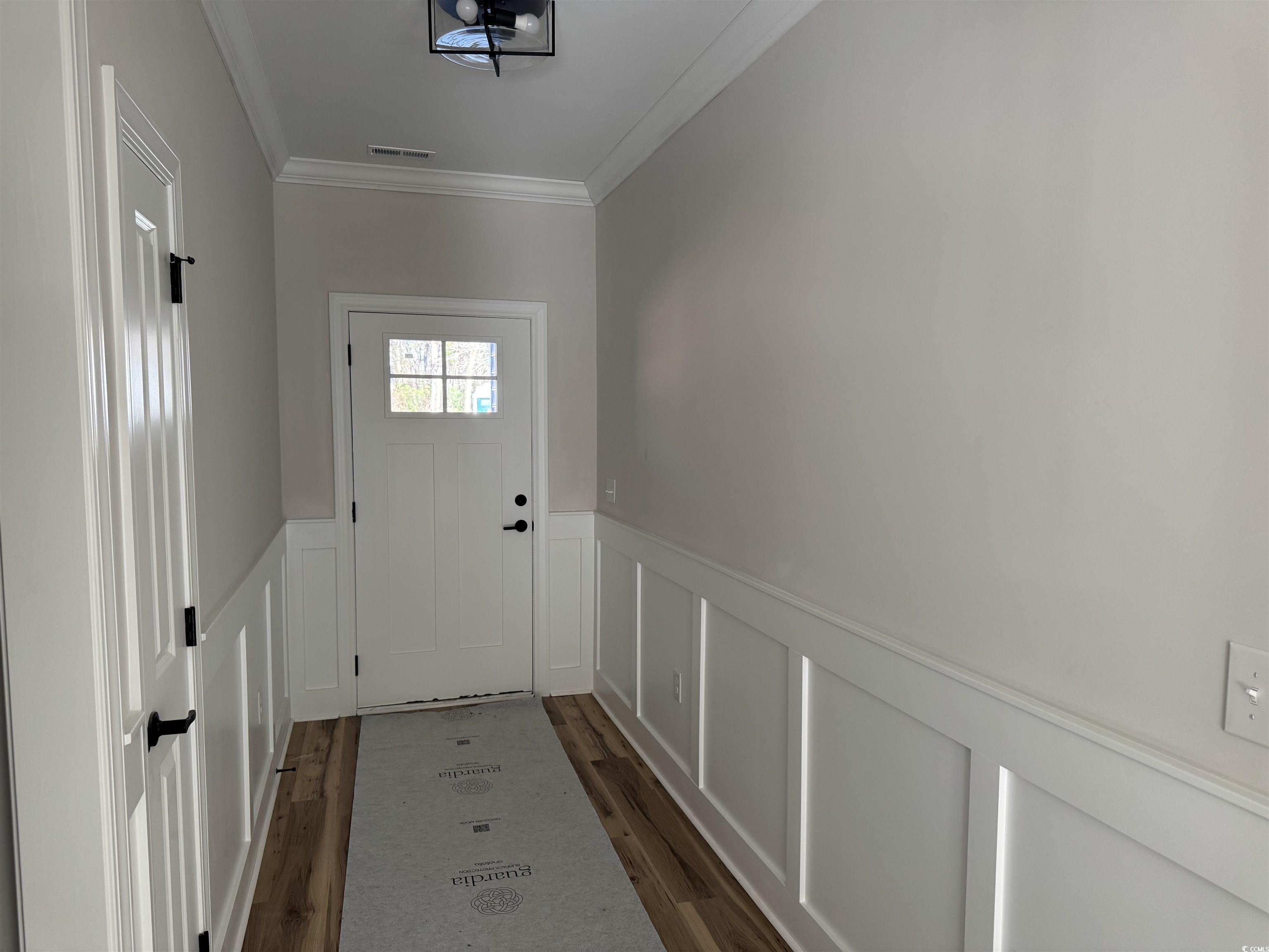 1351 White Oak Lane Galivants Ferry, SC 29544 - Photo 3 of 12 Doorway to outside featuring a wainscoted wall, a decorative wall, ornamental molding, and wood finished floors