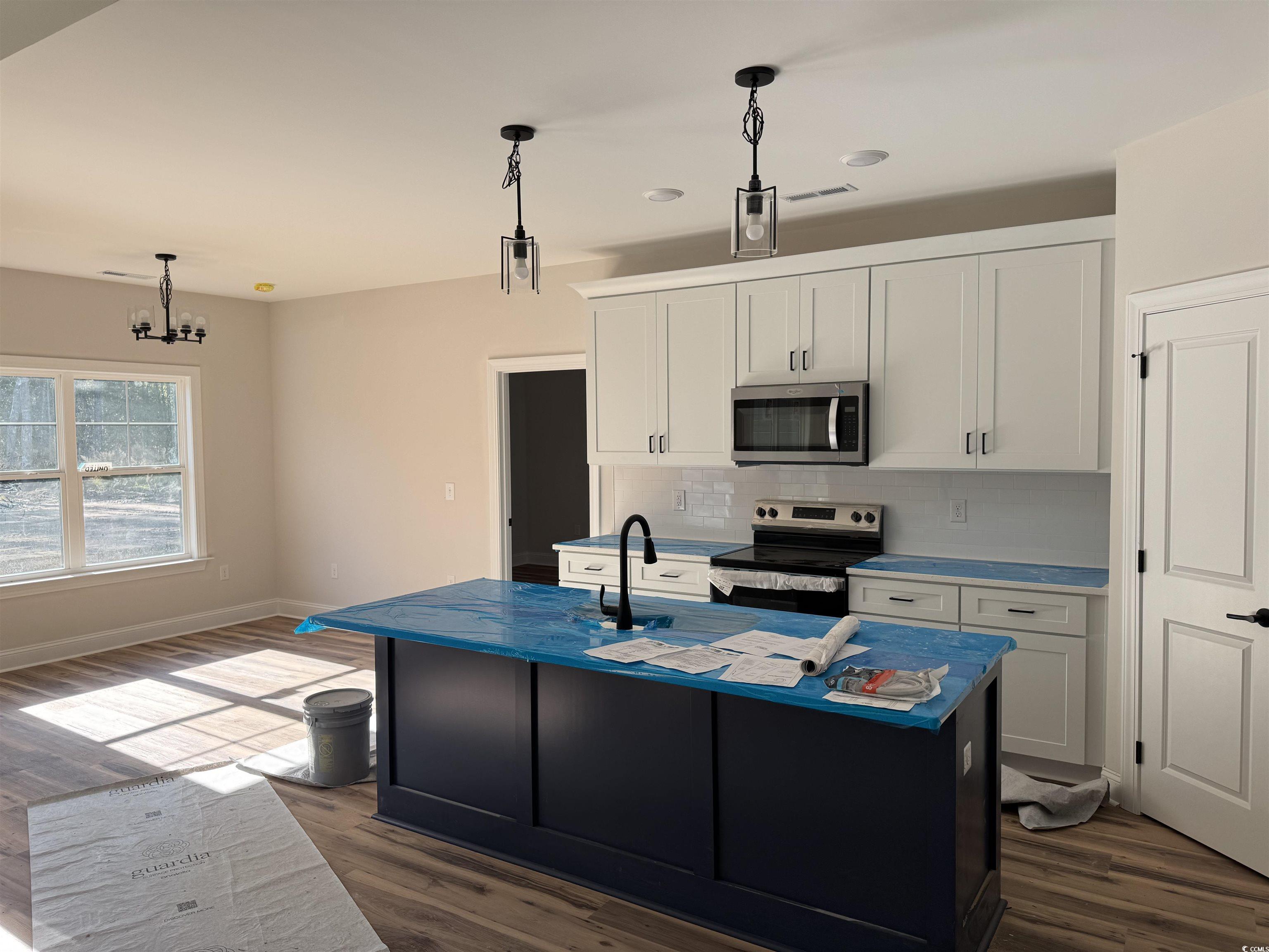 1351 White Oak Lane Galivants Ferry, SC 29544 - Photo 6 of 12 Kitchen featuring stainless steel appliances, white cabinetry, hanging light fixtures, and an island with sink