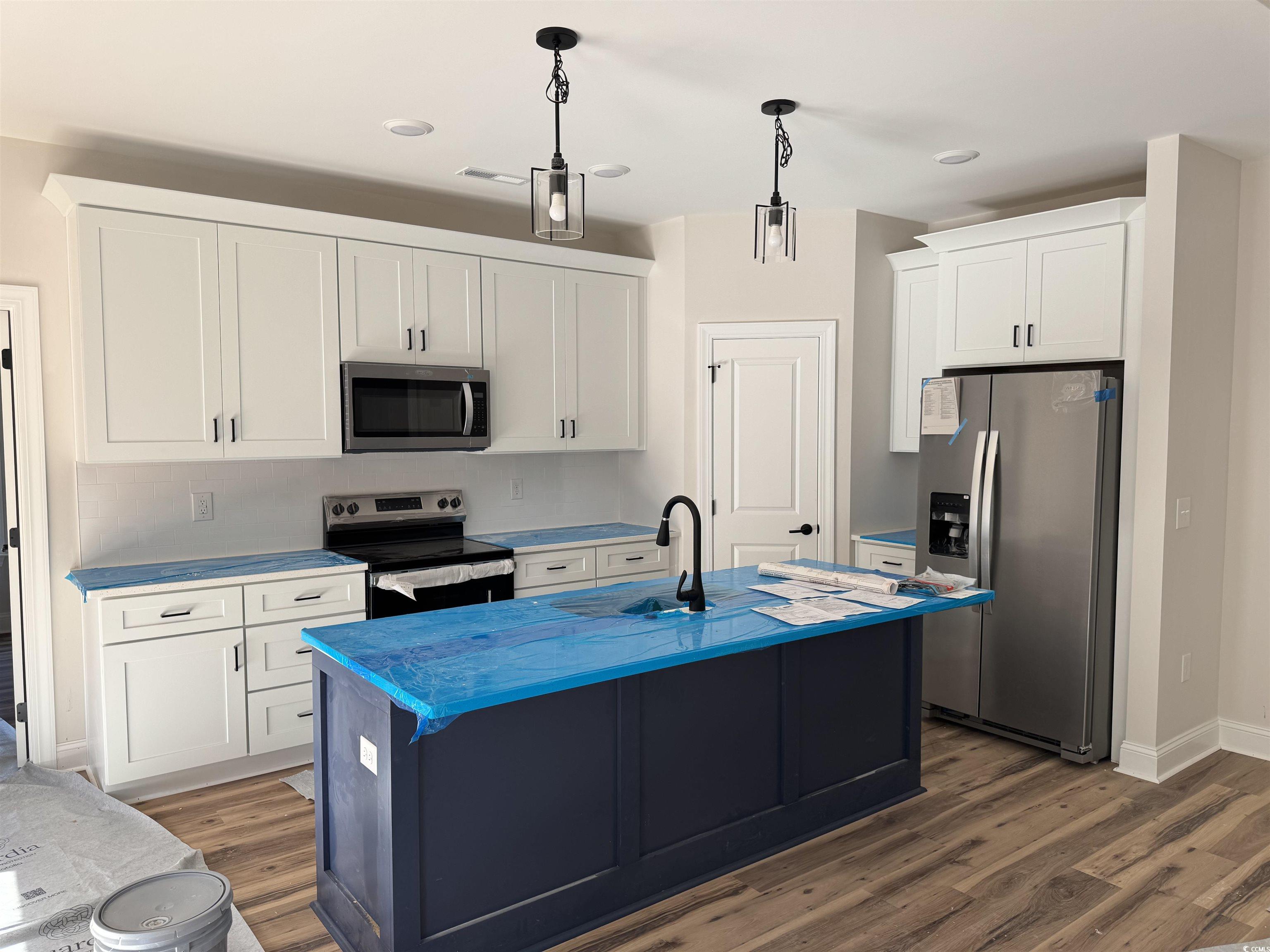 1351 White Oak Lane Galivants Ferry, SC 29544 - Photo 7 of 12 Kitchen featuring appliances with stainless steel finishes, white cabinets, pendant lighting, a kitchen island with sink, and light countertops