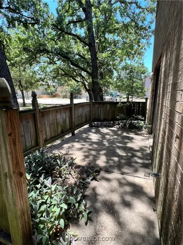 a view of a backyard with large trees and wooden fence