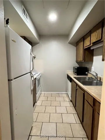 a kitchen with a refrigerator a stove top oven and cabinets