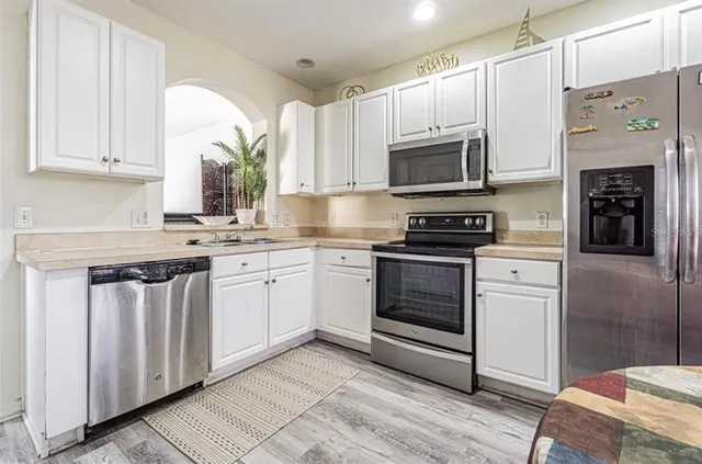 a kitchen with cabinets stainless steel appliances and wooden floor