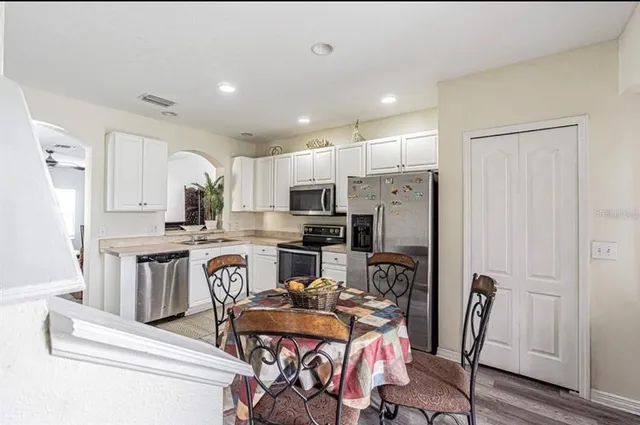 a kitchen with stainless steel appliances granite countertop a refrigerator a stove top oven a sink and chairs