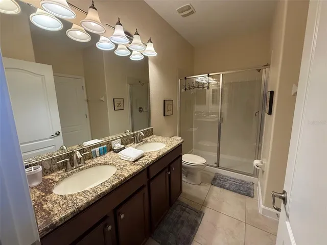 a bathroom with a granite countertop double vanity sink mirror and toilet
