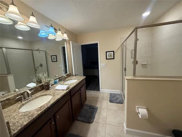 a bathroom with a granite countertop sink a large mirror and a shower