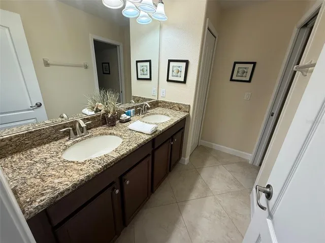 a bathroom with a granite countertop double vanity sink and a mirror