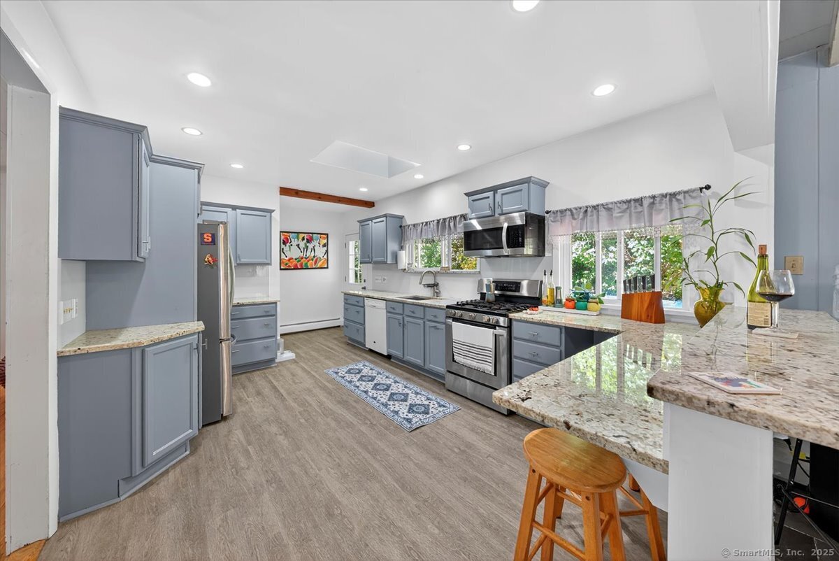 153 Short Woods Road New Fairfield, CT 06812 - Photo 14 of 38 a kitchen with stainless steel appliances granite countertop a stove top oven a sink a refrigerator and white cabinets with wooden floor