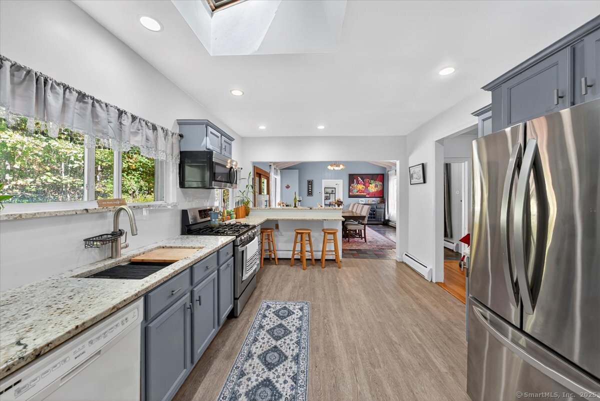153 Short Woods Road New Fairfield, CT 06812 - Photo 30 of 38 a kitchen with stainless steel appliances granite countertop a refrigerator a sink dishwasher a stove and white countertops with wooden floor