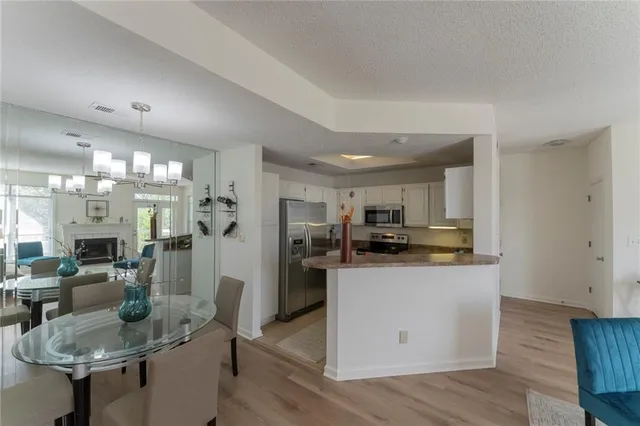 a kitchen with stainless steel appliances kitchen island granite countertop a refrigerator a stove top oven a sink dishwasher and white cabinets with wooden floor