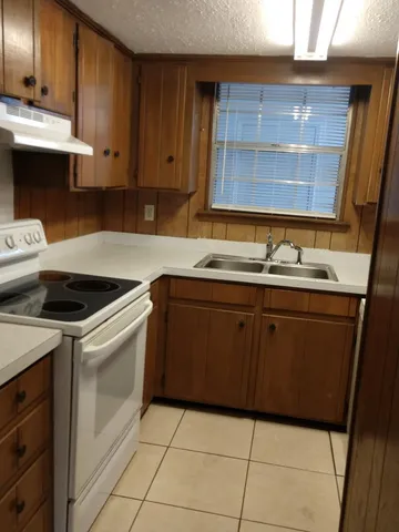 a kitchen with a sink a stove cabinets and wooden floor