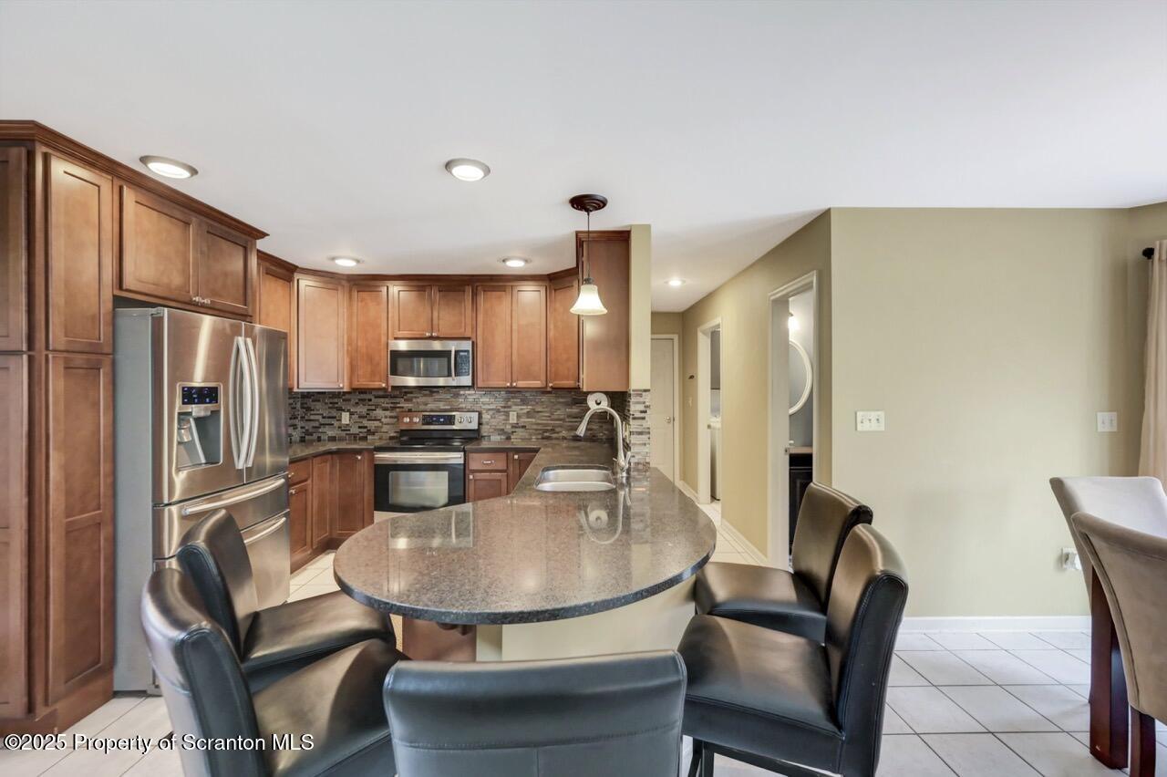 104 Beech Tree Circle Clarks Summit, PA 18411 - Photo 30 of 91 a kitchen with stainless steel appliances granite countertop a refrigerator a stove a sink dishwasher with a dining table and chairs