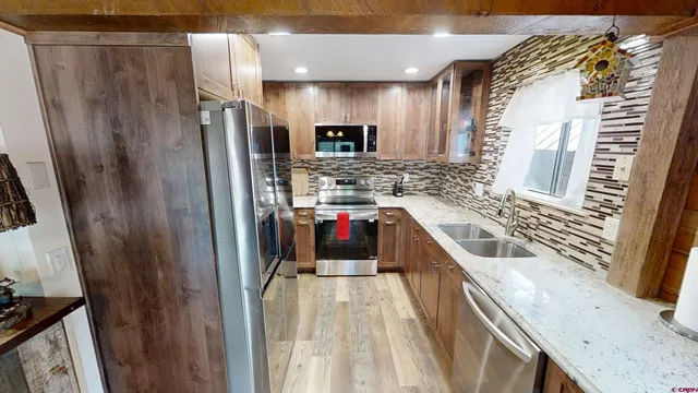a kitchen with stainless steel appliances a refrigerator a sink a stove and cabinets