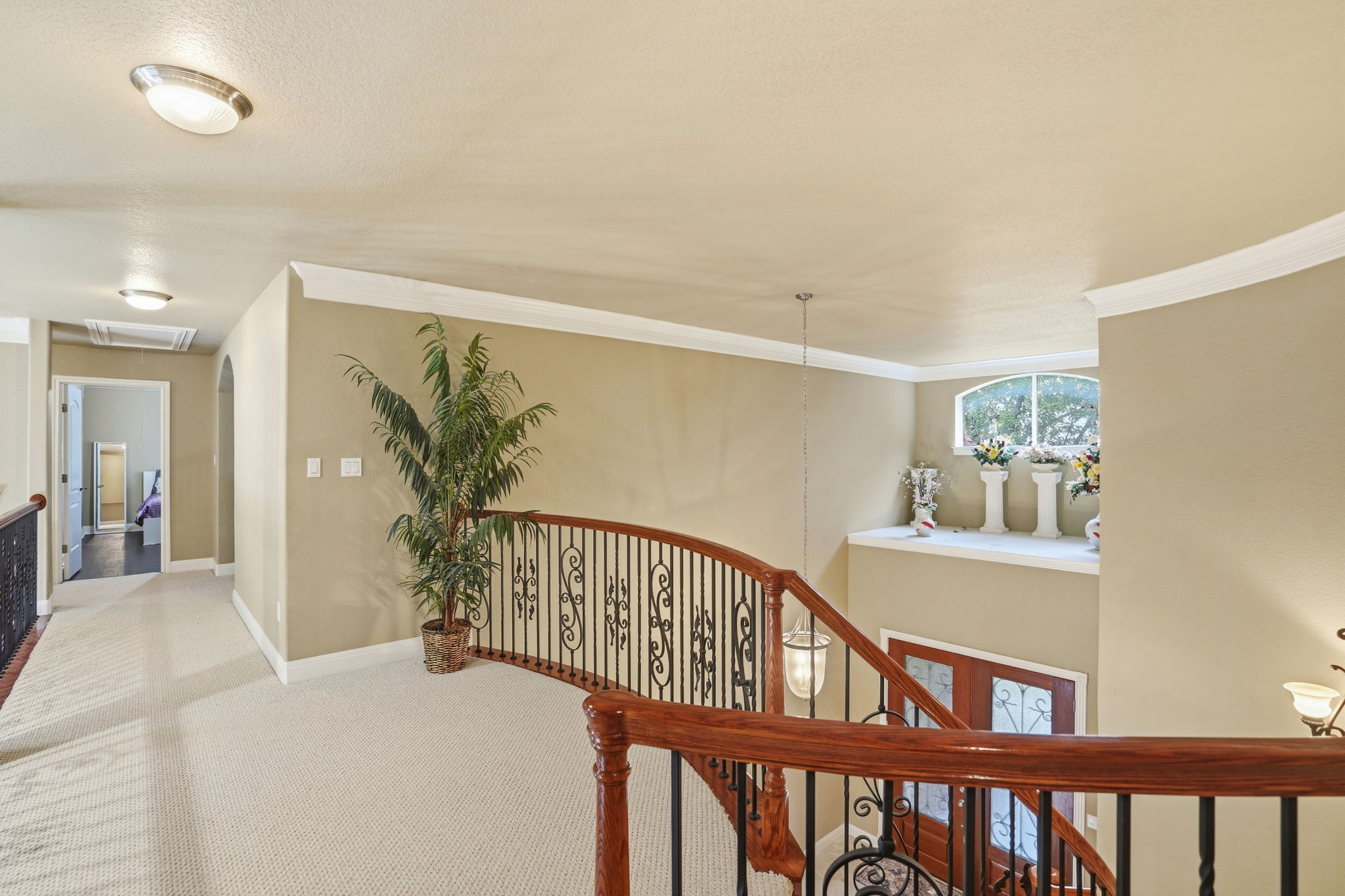 222 Vailco Lane Austin, TX 78738 - Photo 7 of 39 Upper-level landing featuring a curved staircase with wrought iron balusters and a wood-finish handrail