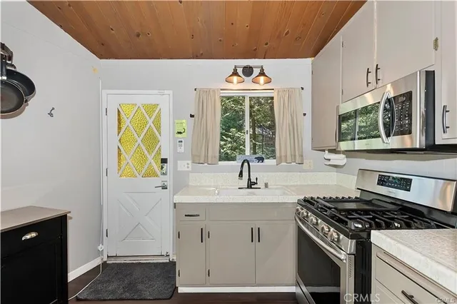 a kitchen with stainless steel appliances granite countertop a sink and a stove next to a window