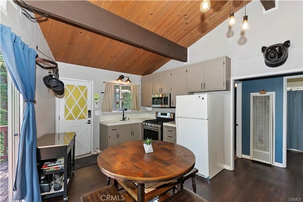 28393 Larchmont Lane Lake Arrowhead, CA 92352 - Photo 6 of 25 a kitchen with a refrigerator a stove and a dining table with wooden floor