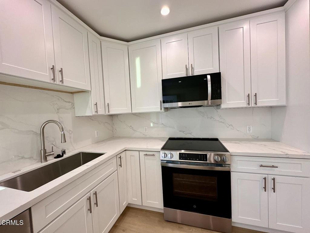 17451 Keswick Street Northridge, CA 91325 - Photo 4 of 8 a kitchen with white cabinets and stainless steel appliances