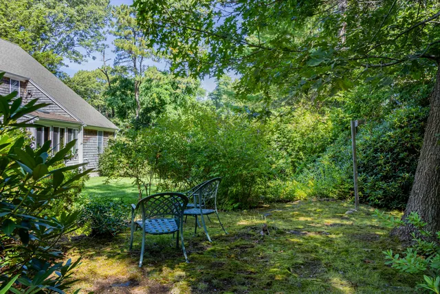 a backyard of a house with table and chairs under an umbrella