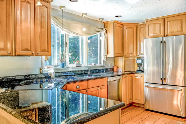 a kitchen with stainless steel appliances granite countertop a refrigerator a sink and a stove top oven