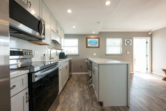 a kitchen with stainless steel appliances granite countertop a sink a stove and a wooden floors