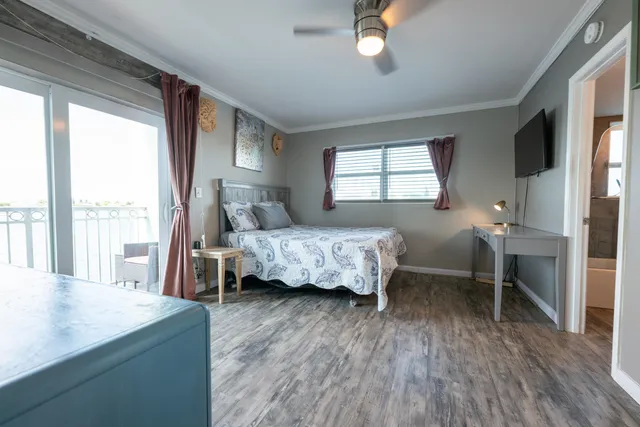 a bedroom with a bed and a large window with wooden floor