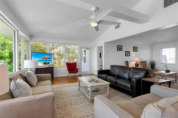 a living room with furniture ceiling fan and a large window