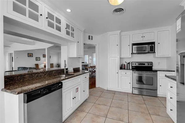 a kitchen with granite countertop a sink stainless steel appliances and white cabinets