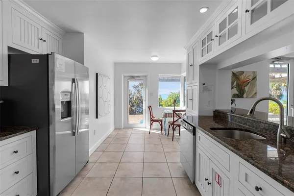 a kitchen with granite countertop a refrigerator a sink a stove and dining table with wooden floor