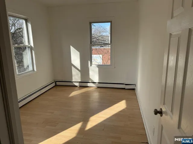 a view of an empty room with window and wooden floor
