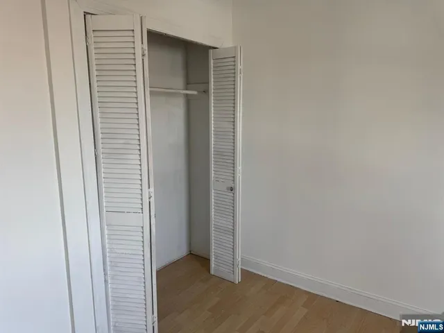 an empty room with wooden floor and closet