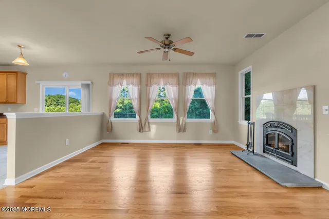 a view of a livingroom with a fireplace a ceiling fan and windows