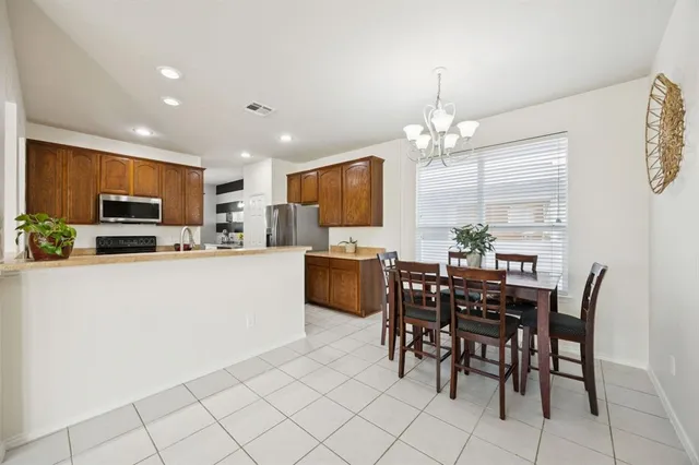 a kitchen with kitchen island granite countertop stainless steel appliances a stove a sink a microwave a dining table and chairs