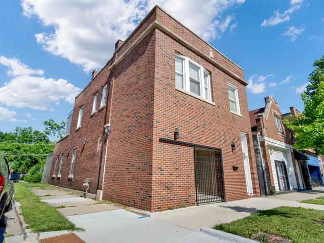 a view of a house with brick walls plants and large tree