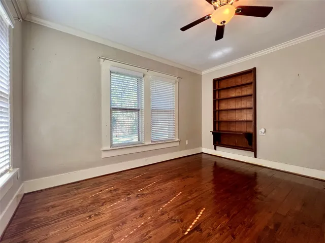 an empty room with wooden floor chandelier fan and windows