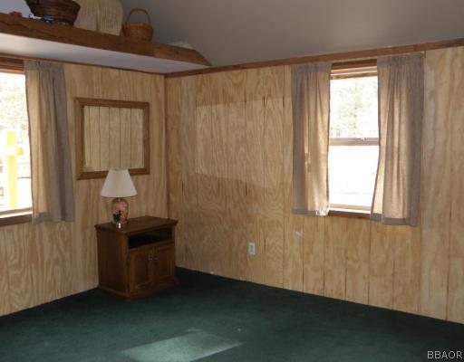 536 Riverside Avenue Sugarloaf, CA 92386 - Photo 4 of 12 Living Room. Rustic wood panelling and dark green carpeting gives this home a "cabiny" look.