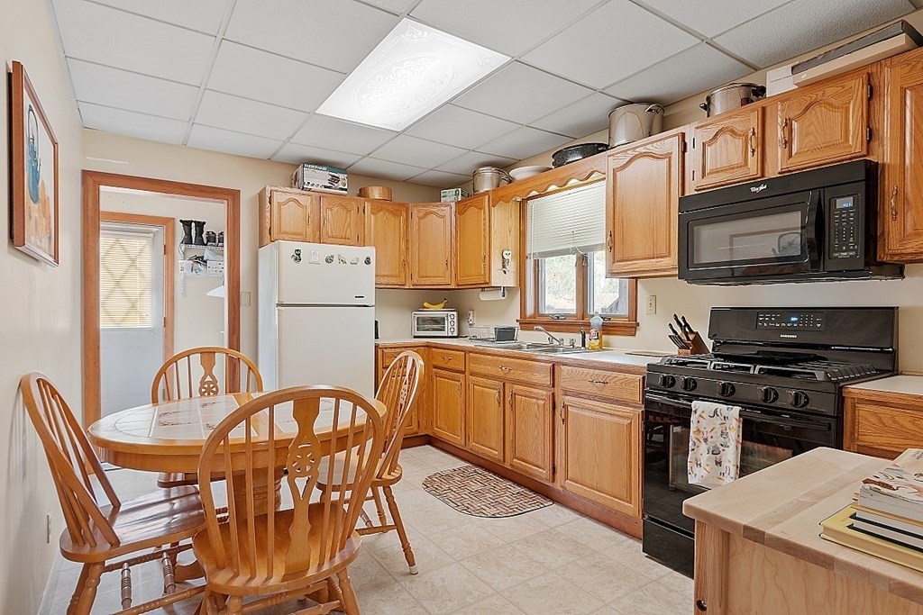 2 Bond Place Saugus, MA 01906 - Photo 12 of 42 a kitchen with stainless steel appliances granite countertop a stove a refrigerator a sink dishwasher a dining table and chairs with wooden floor