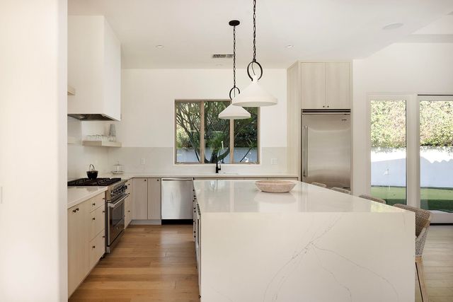 a kitchen with stainless steel appliances granite countertop a sink and a refrigerator