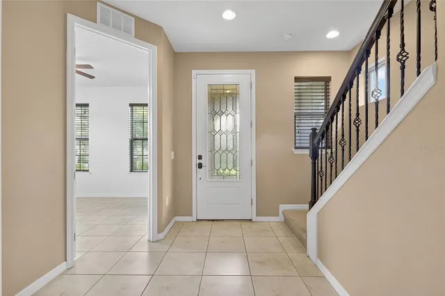 a view of an entryway with wooden floor leading to a furnished livingroom and windows