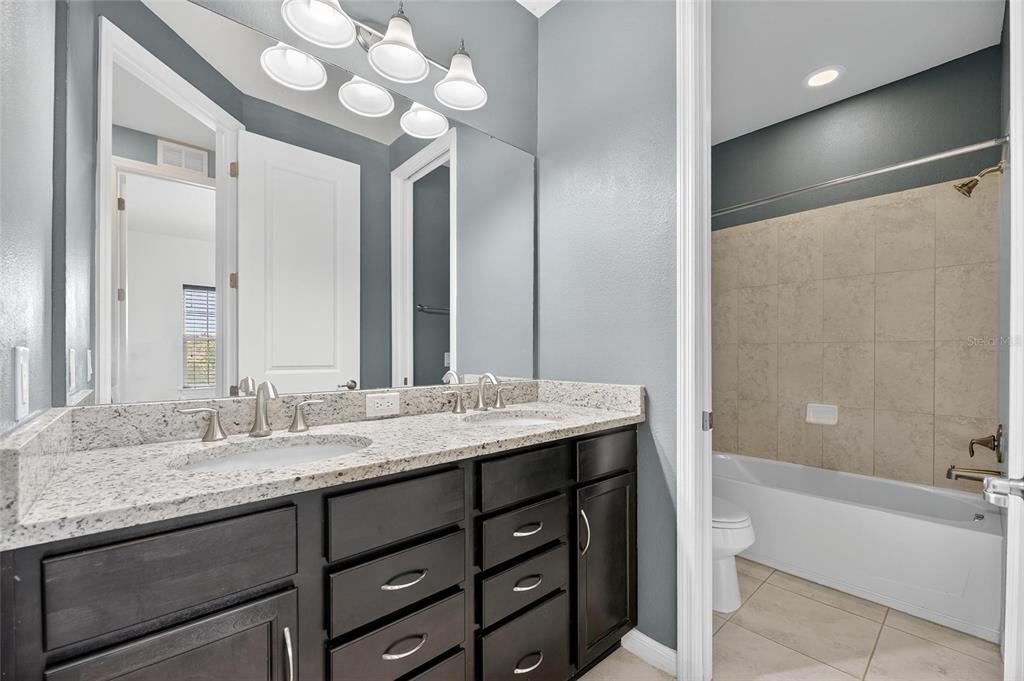 5811 Caldera Ridge Drive Lithia, FL 33547 - Photo 23 of 44 a bathroom with a granite countertop sink a large mirror and a bathtub