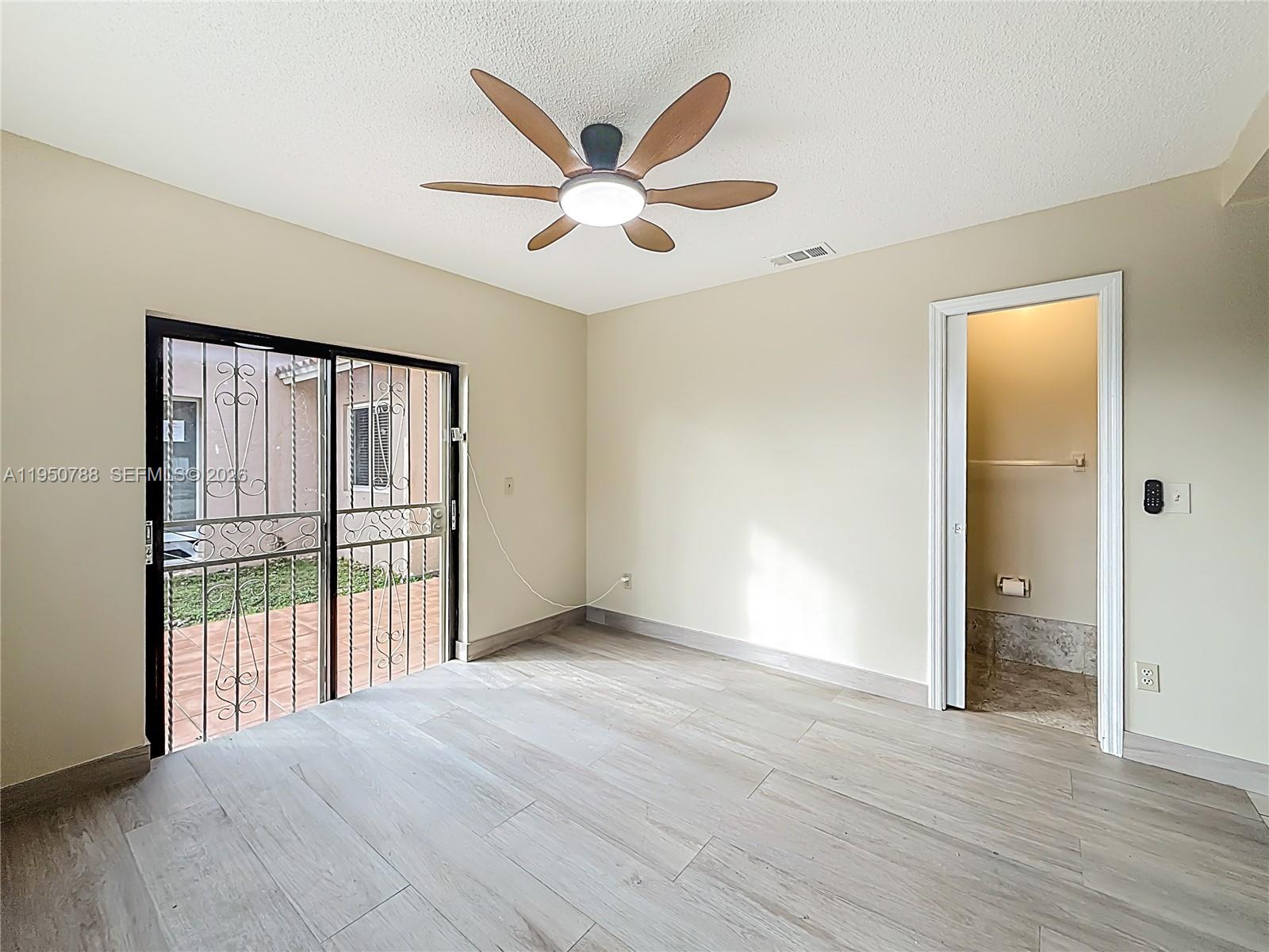 12787 Northwest 10th Lane Miami, FL 33182 - Photo 9 of 48 an empty room with wooden floor fan and windows