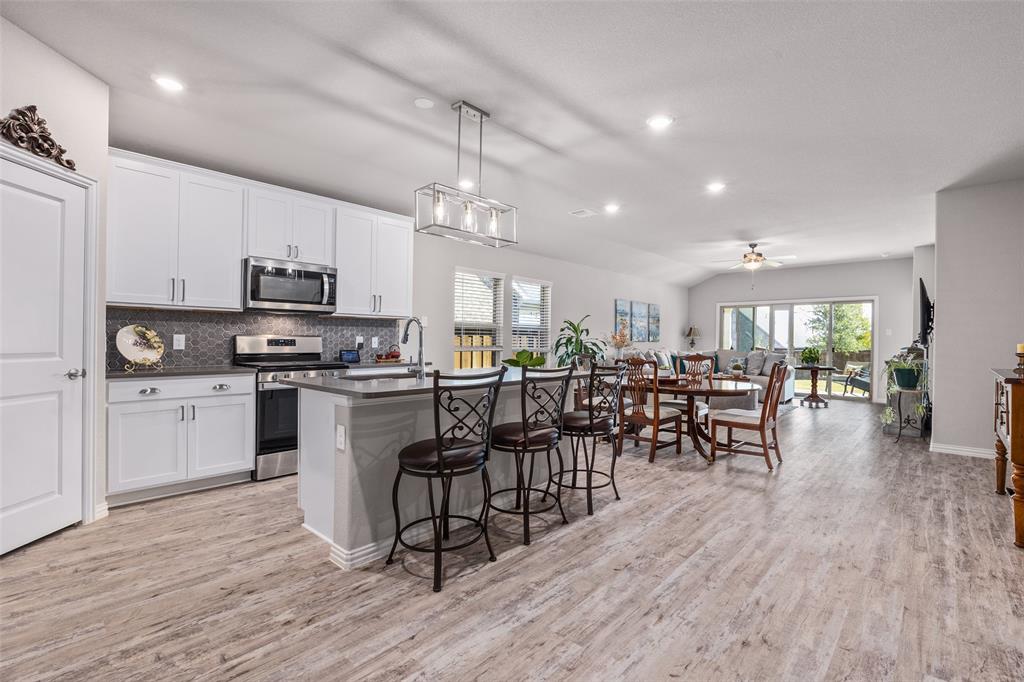 10505 Trail Ridge Drive Fort Worth, TX 76126 - Photo 3 of 37 a kitchen with stainless steel appliances a dining table chairs stove microwave and cabinets