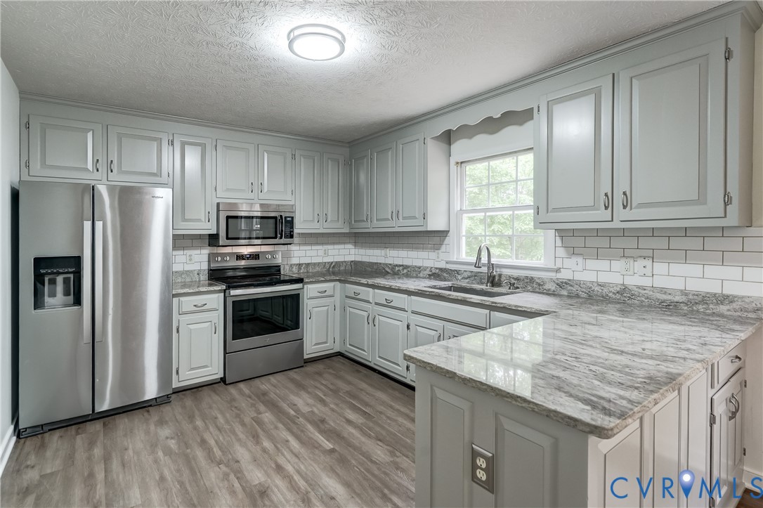 3820 Mt Pleasant Road Providence Forge, VA 23140 - Photo 2 of 40 a kitchen with stainless steel appliances granite countertop a stove a sink dishwasher a refrigerator and a microwave oven with wooden floor