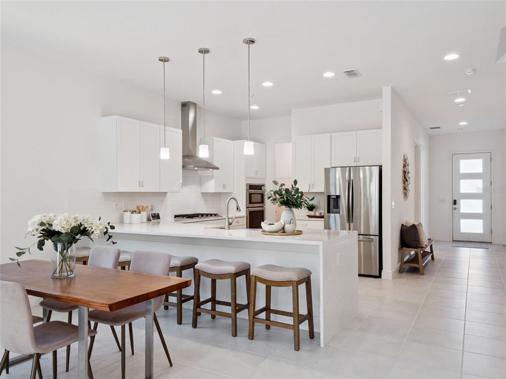2932 Tupelo Loop St. Cloud, FL 34772 - Photo 12 of 47 a kitchen with stainless steel appliances kitchen island a table and chairs in it