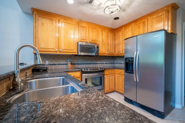 a kitchen with stainless steel appliances granite countertop a sink a stove and a refrigerator