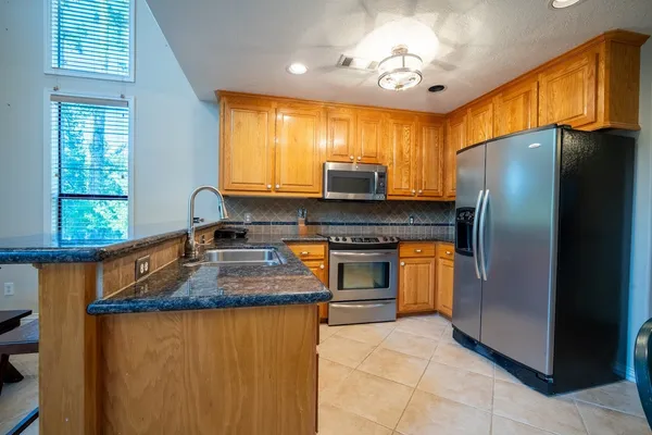a kitchen with stainless steel appliances granite countertop a refrigerator a sink dishwasher a stove and a refrigerator