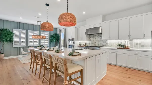 a kitchen with stainless steel appliances granite countertop a stove a sink dishwasher a dining table and chairs with wooden floor