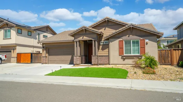 a view of a white house with a small yard and a large parking space